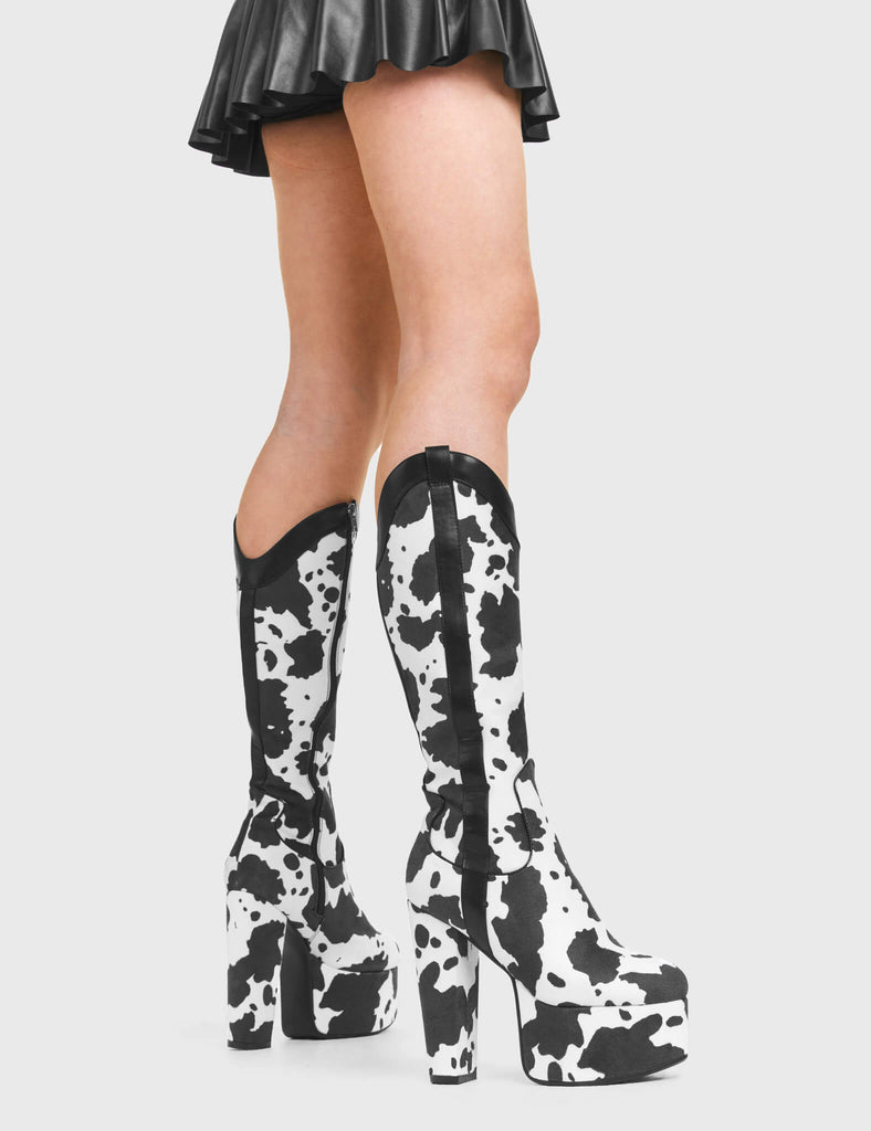 THE WILD ICON
  
  Cowgirl Platform Knee High Boots in Cow Print faux suede. These vegan Platform Boots feature an ICONIC western cow print and High Platform sole and heel, the only choice for festival goers. Made with eco-friendly materials and 100% cruelty-free, these boots are as ethical as they are wild!
  
  
  - Platform Height: 2.5 inch
  - Heel Height: 5.5 inch 
  - Knee High length
  - Black zipper 
  - Western neck
  - Platform sole
  - Pointed toe 
  - 100% vegan 
  
  SKU: LMF 376 - White Cow