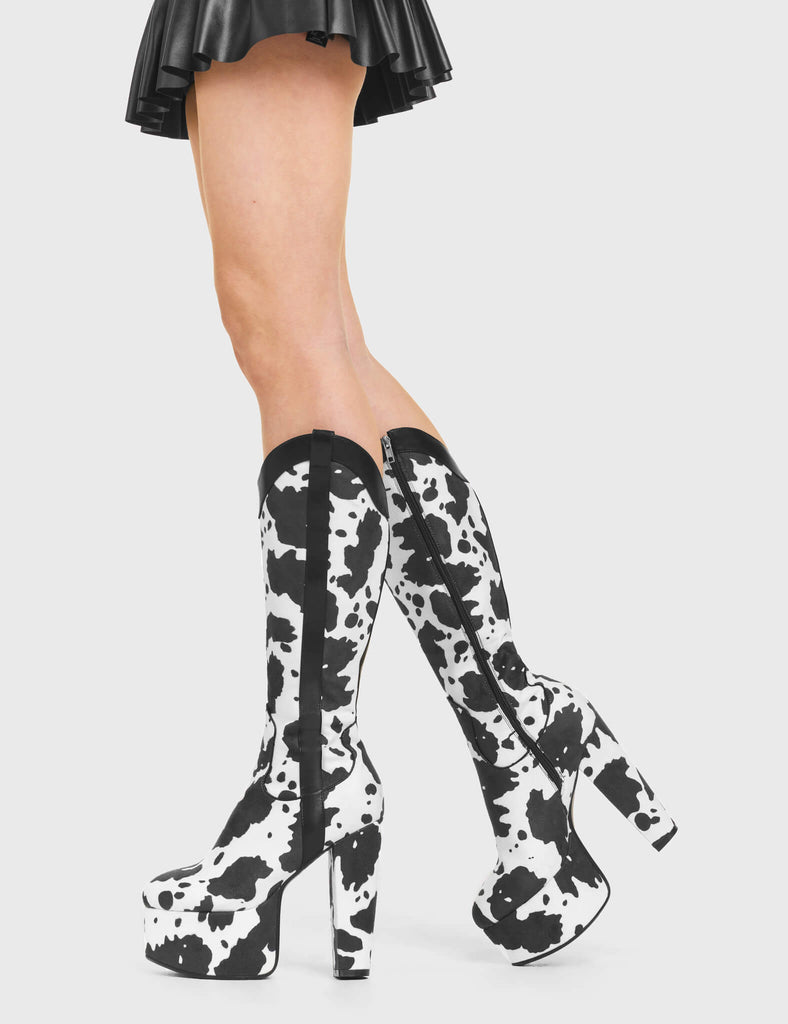 THE WILD ICON
  
  Cowgirl Platform Knee High Boots in Cow Print faux suede. These vegan Platform Boots feature an ICONIC western cow print and High Platform sole and heel, the only choice for festival goers. Made with eco-friendly materials and 100% cruelty-free, these boots are as ethical as they are wild!
  
  
  - Platform Height: 2.5 inch
  - Heel Height: 5.5 inch 
  - Knee High length
  - Black zipper 
  - Western neck
  - Platform sole
  - Pointed toe 
  - 100% vegan 
  
  SKU: LMF 376 - White Cow
