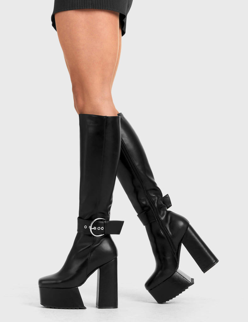 Not Your Basic Boots
  
  Power Over You Platform Knee High Boots in Black faux leather. These platform boots feature a minimalist design, with a strap around the ankle and a silver 'O' ring buckle, the perfect pair with any outfit. Made with eco-friendly materials and 100% cruelty-free
  
  - Platform Height
  - Heel Height
  - Black Zipper
  - Ankle strap and Silver buckle
  - Thigh length
  - Platform sole
  - Shark's teeth grip
  - High Heel
  - 100% vegan 
  
  SKU: LMF 2880 - BlackPU